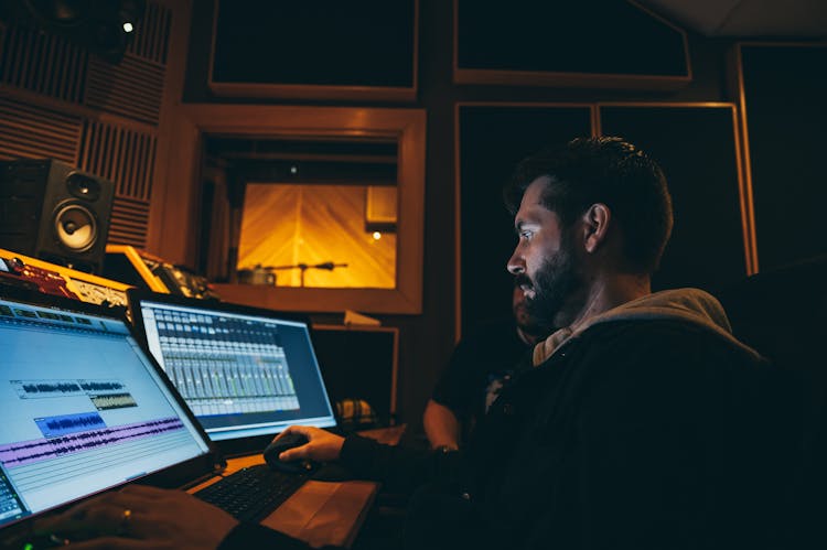 Sound Engineer Using Musical Software On Desktop Computers At Work