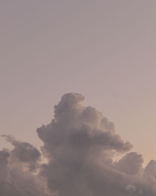 From below picturesque view of shapeless gray clouds with thick texture on white sky in evening time