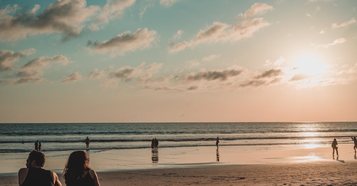 Beautiful sunset view on a Bali beach with people relaxing and enjoying the serene landscape.