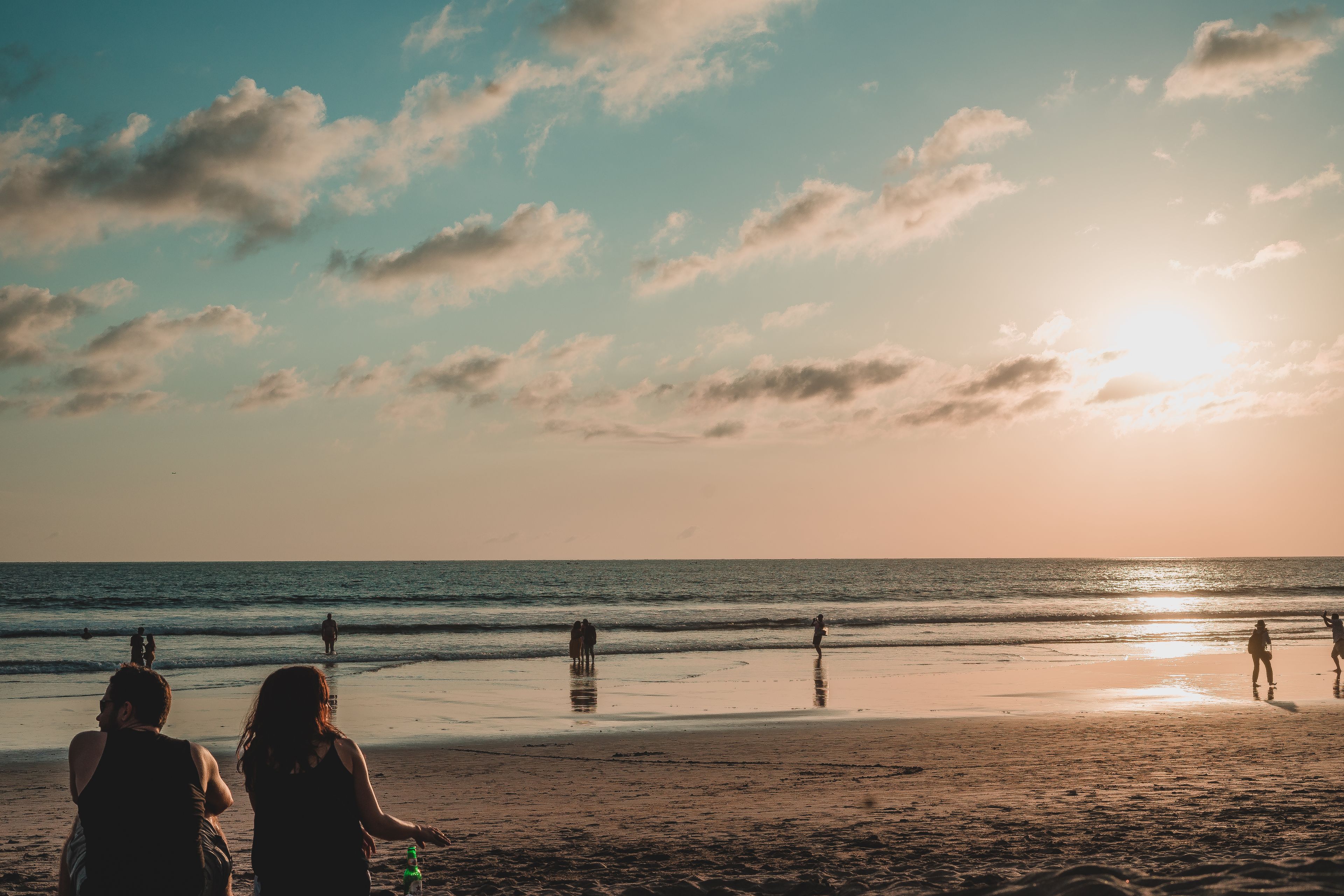 Beautiful sunset view on a Bali beach with people relaxing and enjoying the serene landscape.
