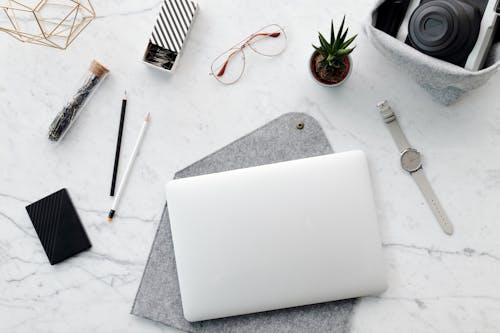 A Laptop Beside Pencils and a Wristwatch