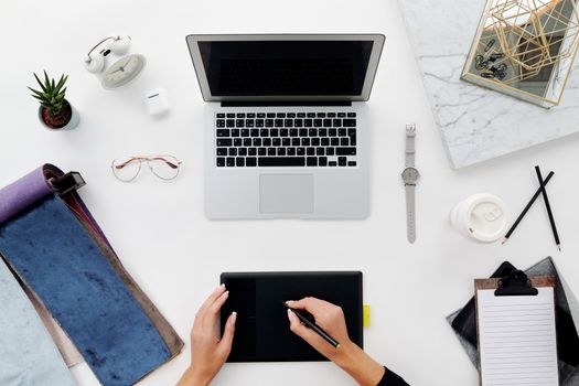Top view of a modern home office setup with a laptop and drawing tablet, perfect for remote work and creative endeavors.