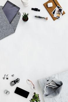 Top view of a minimalist workspace featuring electronic devices and accessories on a white background.