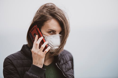 A Woman with a Face Mask Talking on the Phone