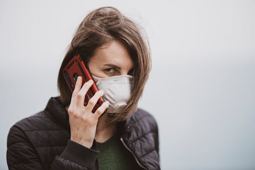 A woman in a face mask talks on her smartphone outdoors, emphasizing pandemic precautions.