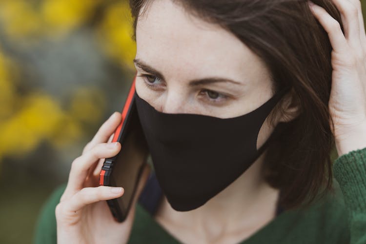 A Woman Wearing A Face Mask While On A Call 