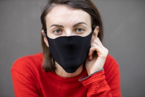 Close-Up Shot of a Woman in Red Sweater Wearing Black Face Mask