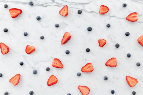 Free Top view of fresh sliced strawberries and blueberries on marble surface. Stock Photo