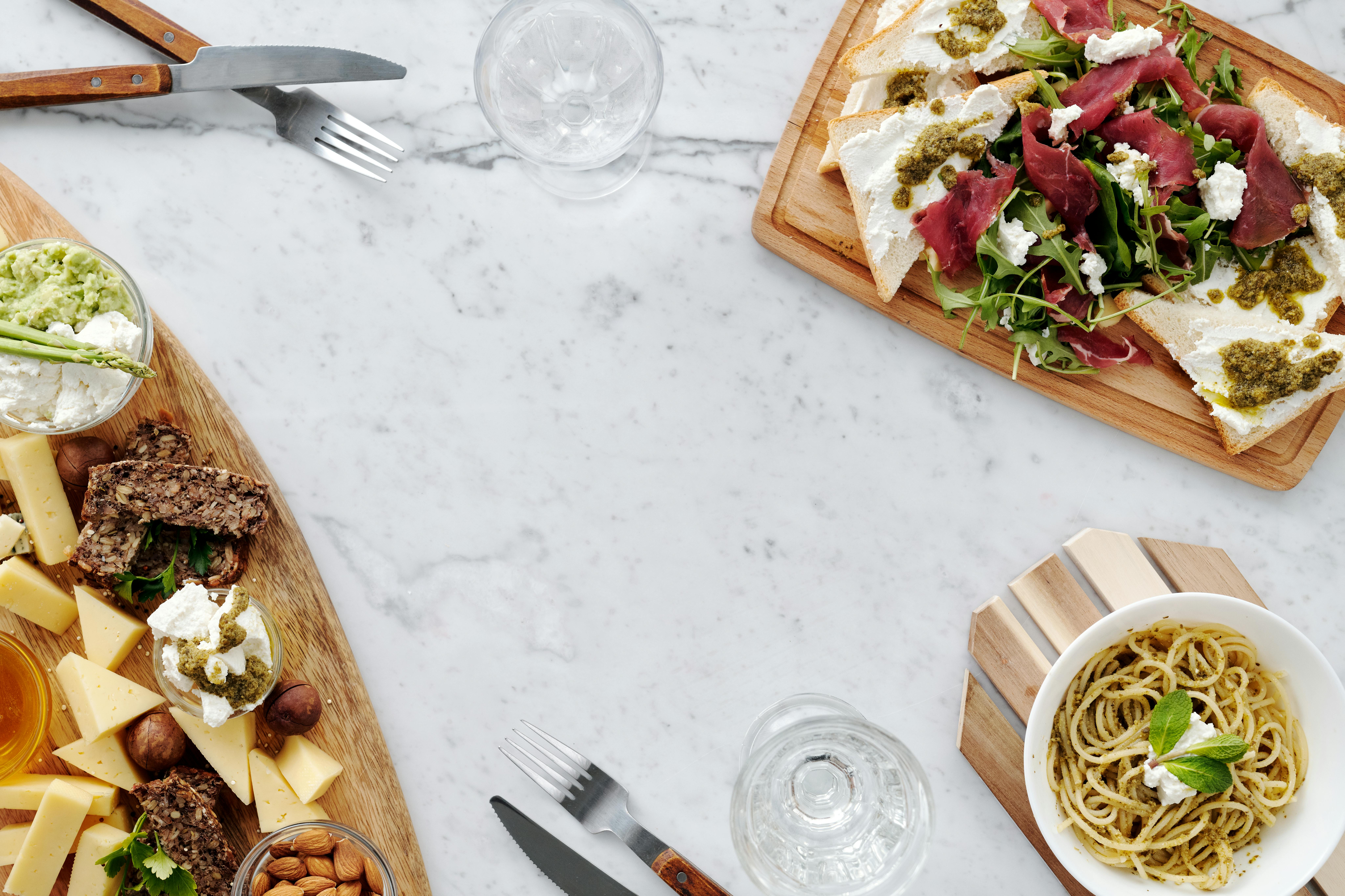 A delicious spread of cheese, pasta, and salad on a marble table.
