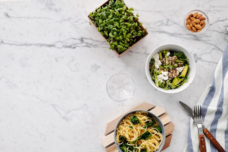 Flat lay of salad and pasta on a marble surface, photo by Luna Lovegood on Pexels