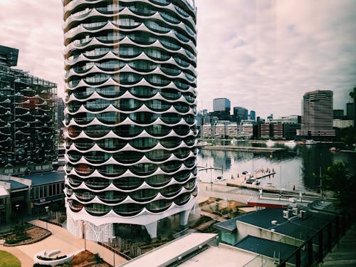 High contemporary building located on city street near river under sky with clouds