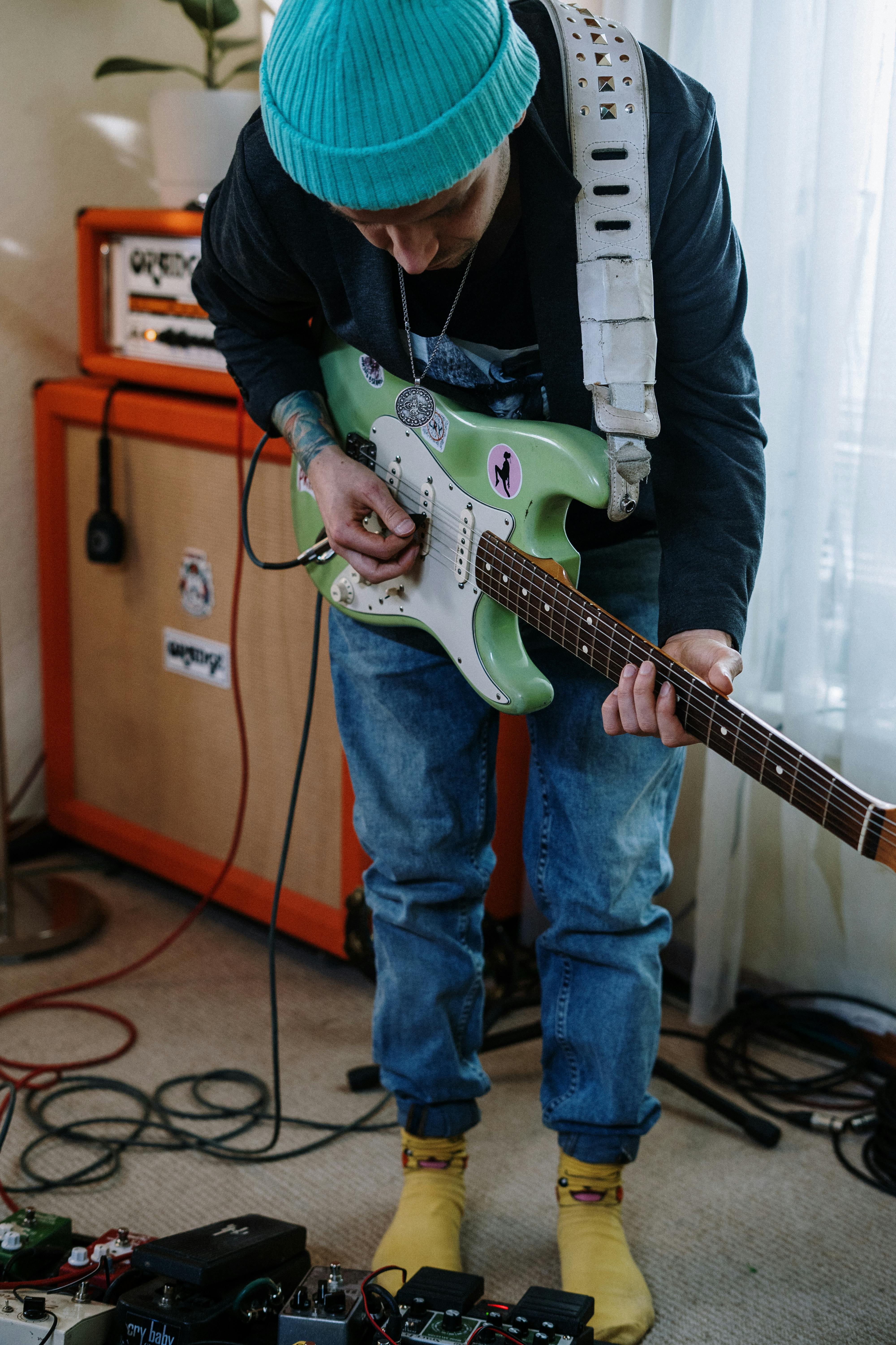 person in blue denim jeans holding white electric guitar