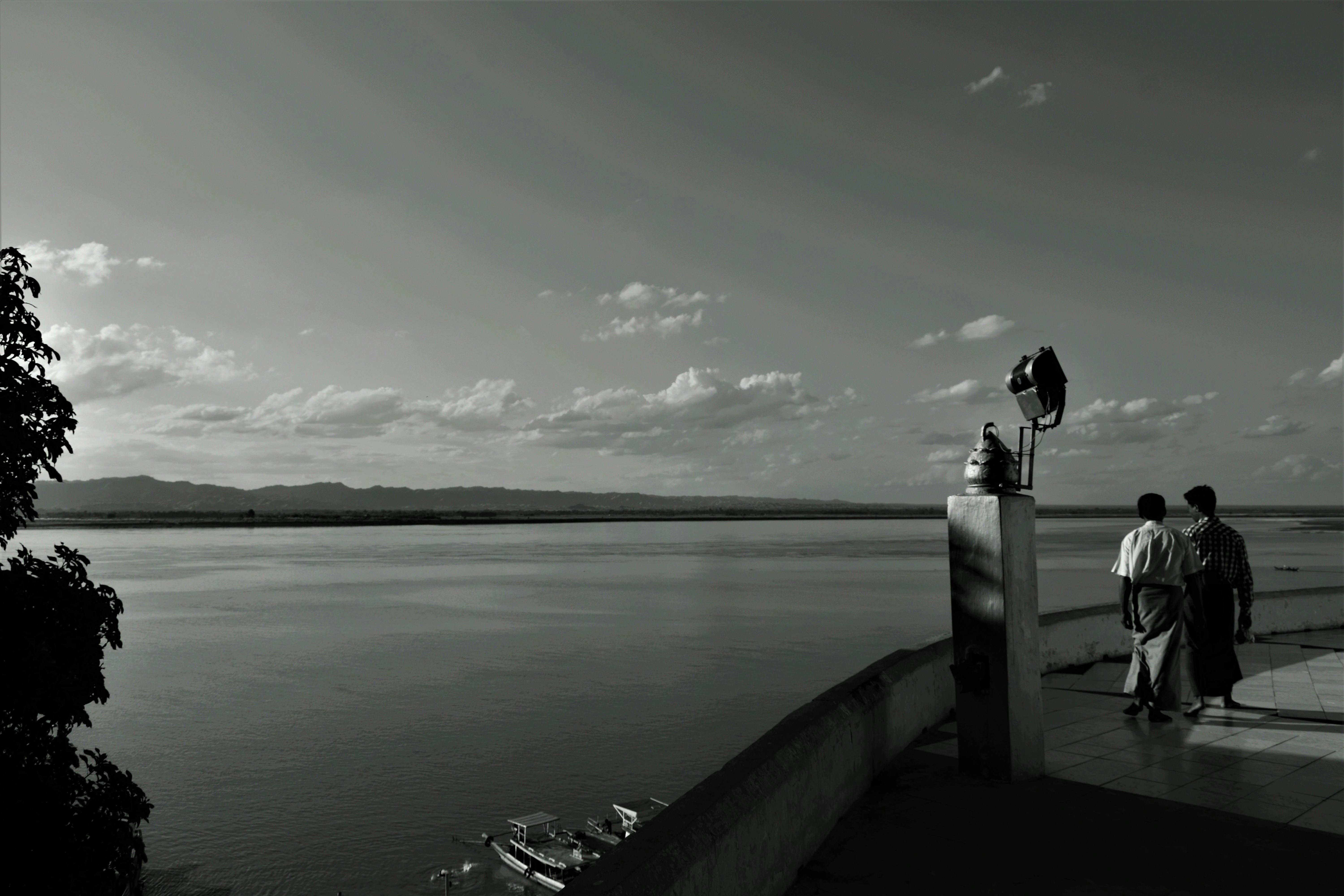 person standing on wooden dock in grayscale photography