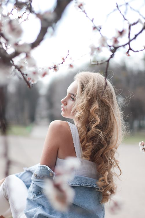 Free Back view of young sensual woman with long blond hair and bare shoulders standing in spring park on sunny day Stock Photo