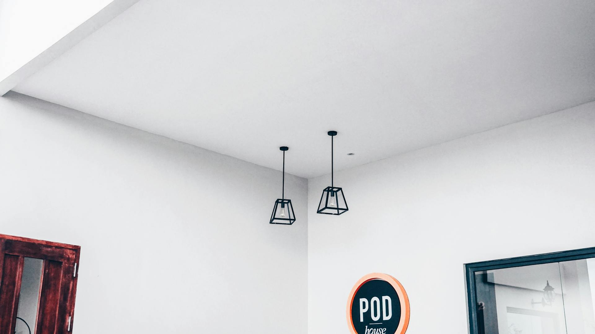 Modern minimalist interior featuring geometric pendant lights and a POD sign.