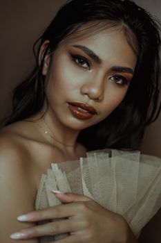 Stylish portrait of an elegant woman with dramatic makeup in a studio setting.