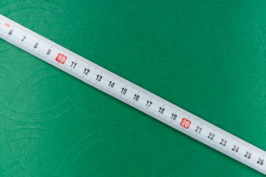 A close-up shot of a tape measure on a textured green background, showing precise measurements.