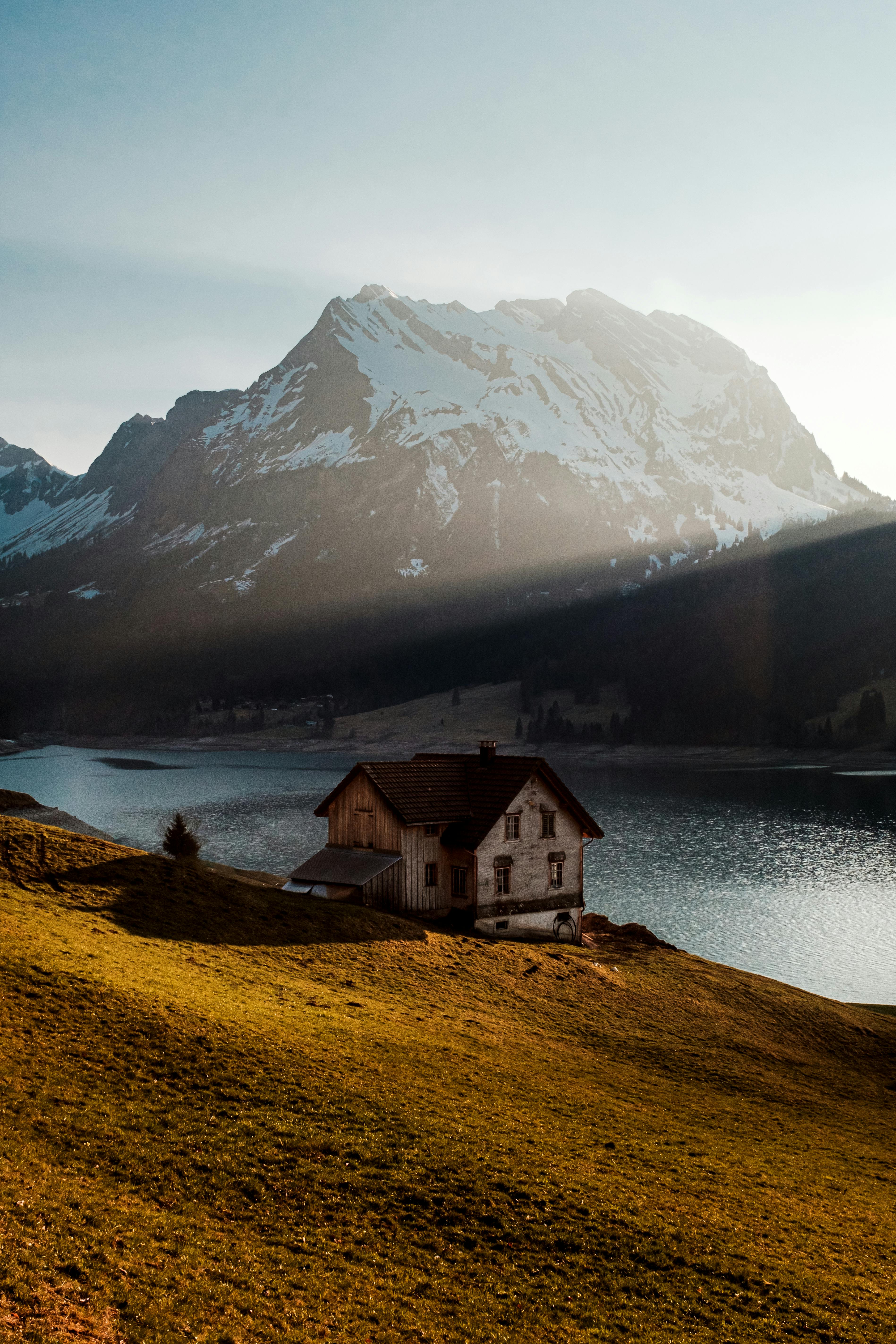 Charming view of a lake house with snow-covered mountains in Innerthal, Switzerland.