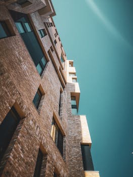 Low-angle view of a modern brick building facade with unique geometric design against a clear sky.
