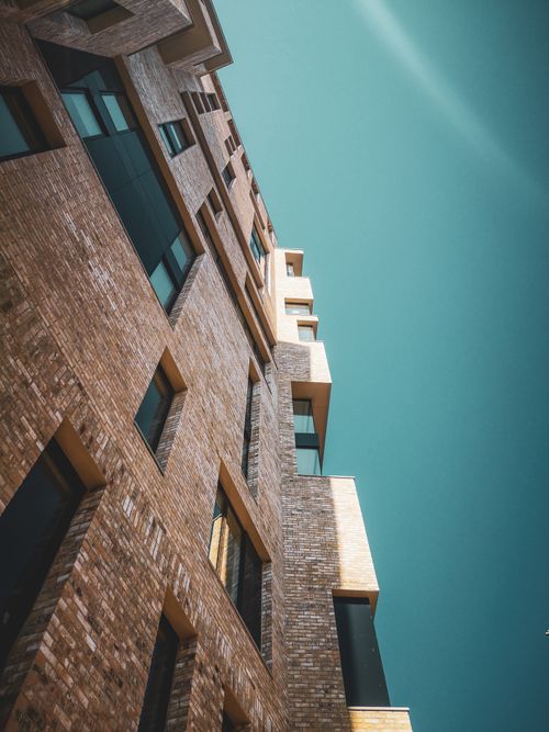 Free From below facade of contemporary residential building with geometric shapes balconies and windows against blue sky in city on sunny day Stock Photo