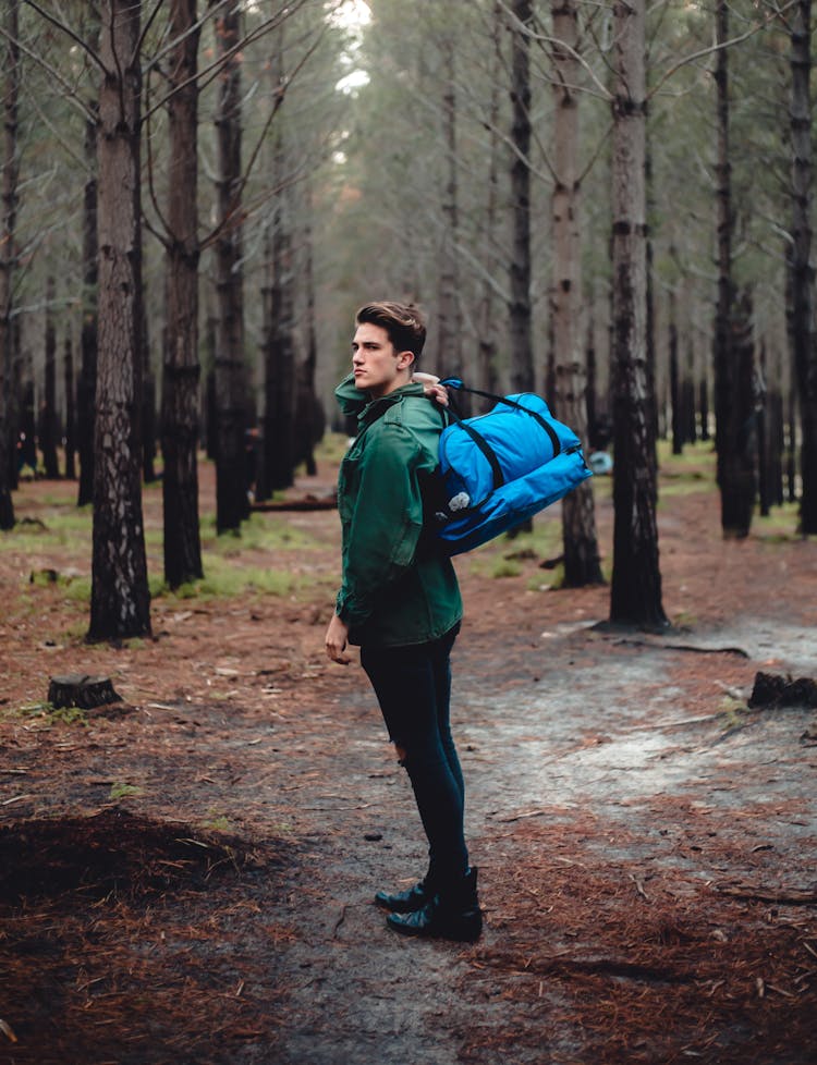 Young Man With Big Bag In Leafless Forest