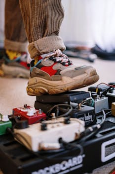 Close-up of a sneaker pressing a guitar pedal in a cozy home music studio.