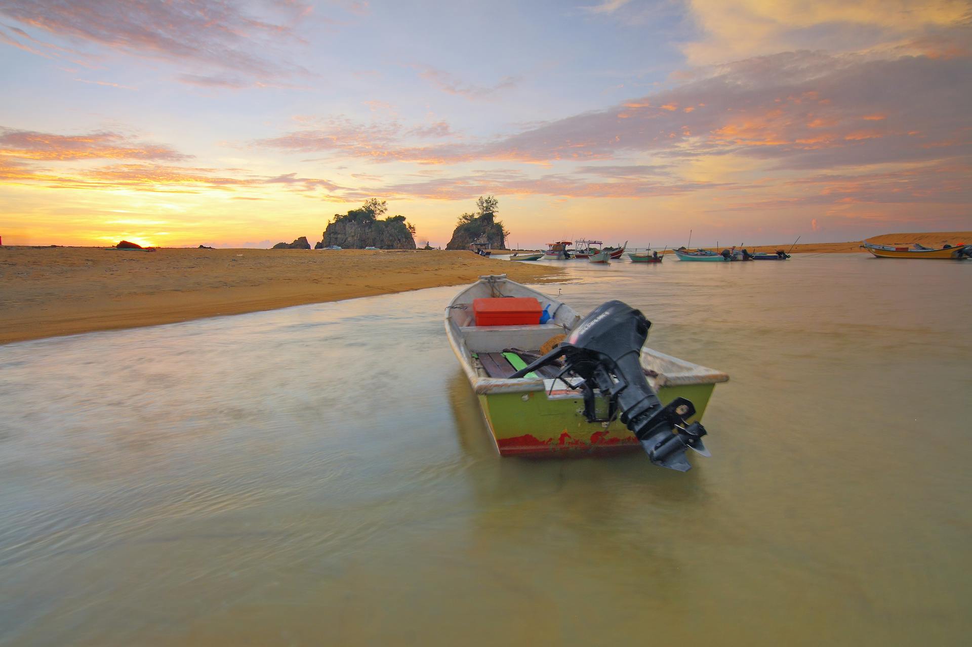 Tranquil sunrise over a scenic beach with boats, ideal for relaxation themes.
