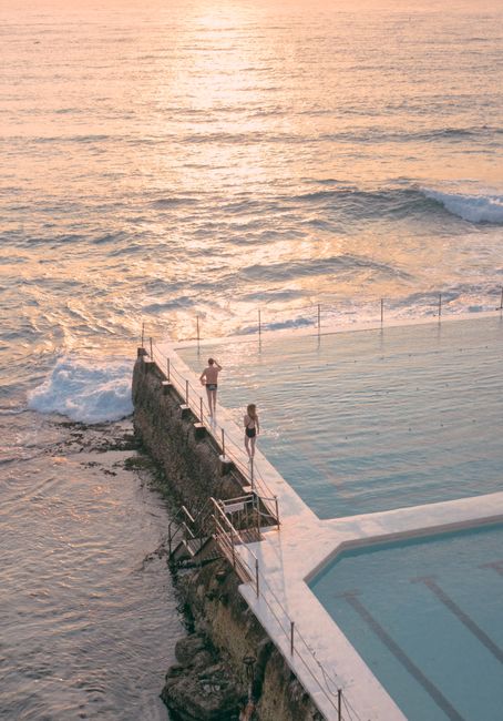 Serene aerial shot of Bondi Icebergs pool with ocean waves at sunrise, capturing a tranquil summer morning.