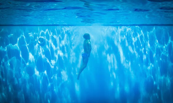 A person swimming underwater in a pool, capturing a serene and dreamlike moment.