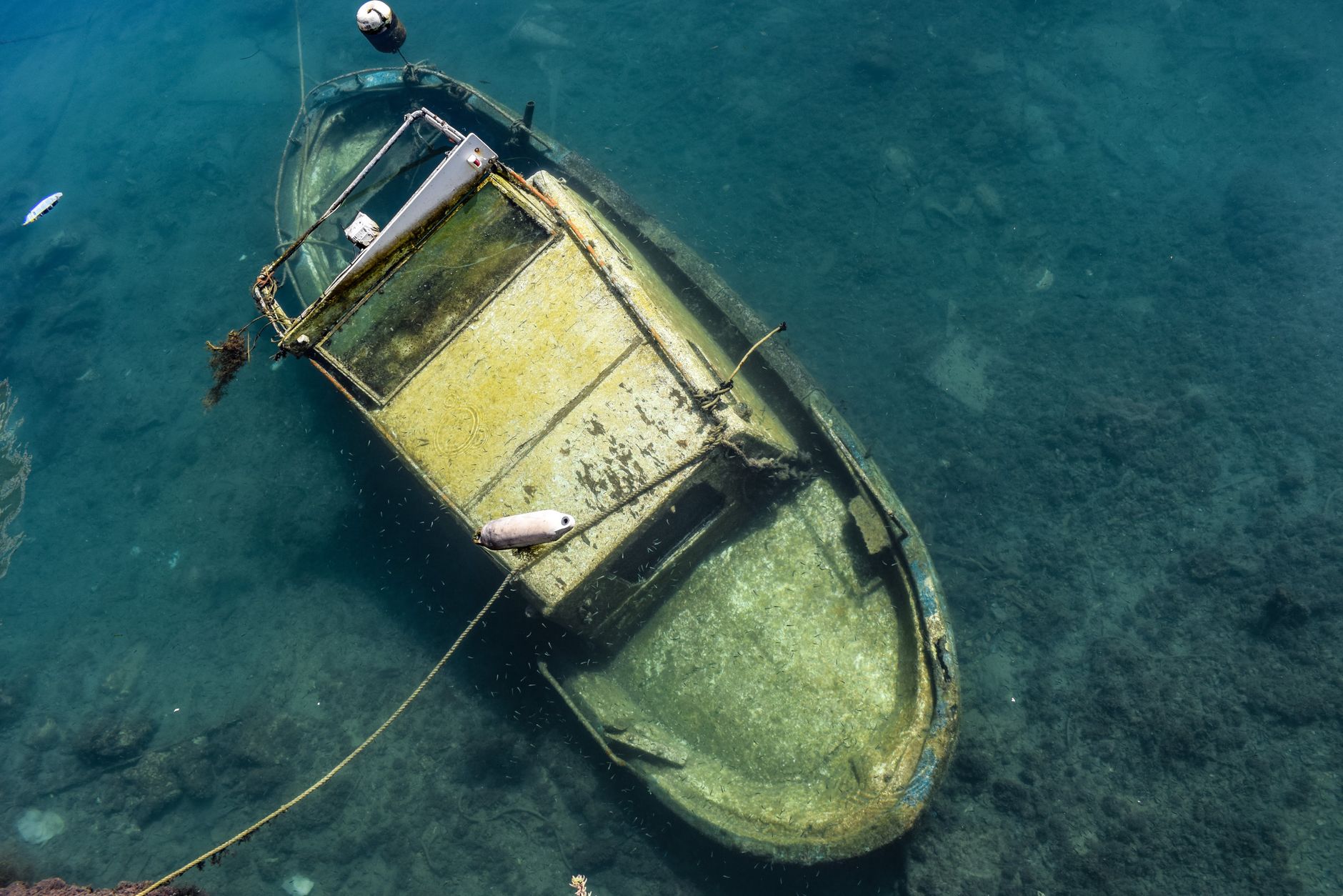From above of old shabby abandoned boat sunken in sea water on sunny day