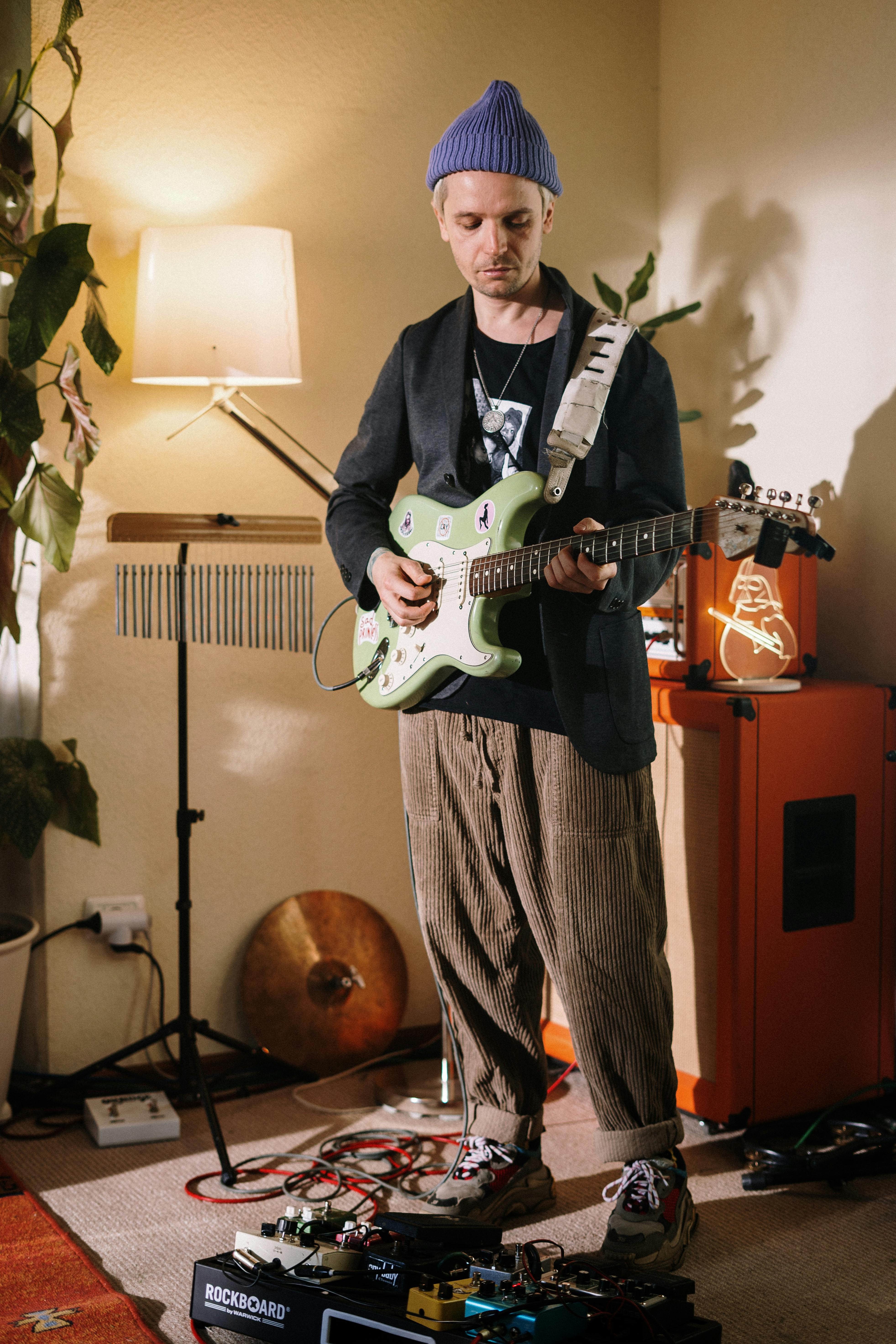 man in black suit jacket playing white electric guitar