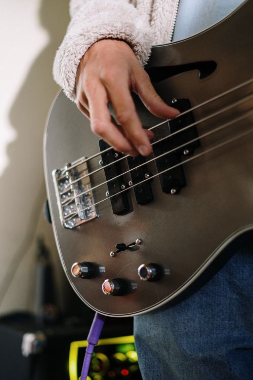 Free Detailed shot of a hand playing an electric bass guitar in a cozy home studio environment. Stock Photo