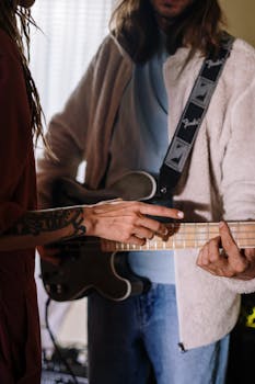 Two musicians collaborate in a home studio, focusing on guitar practice with attentive detail.