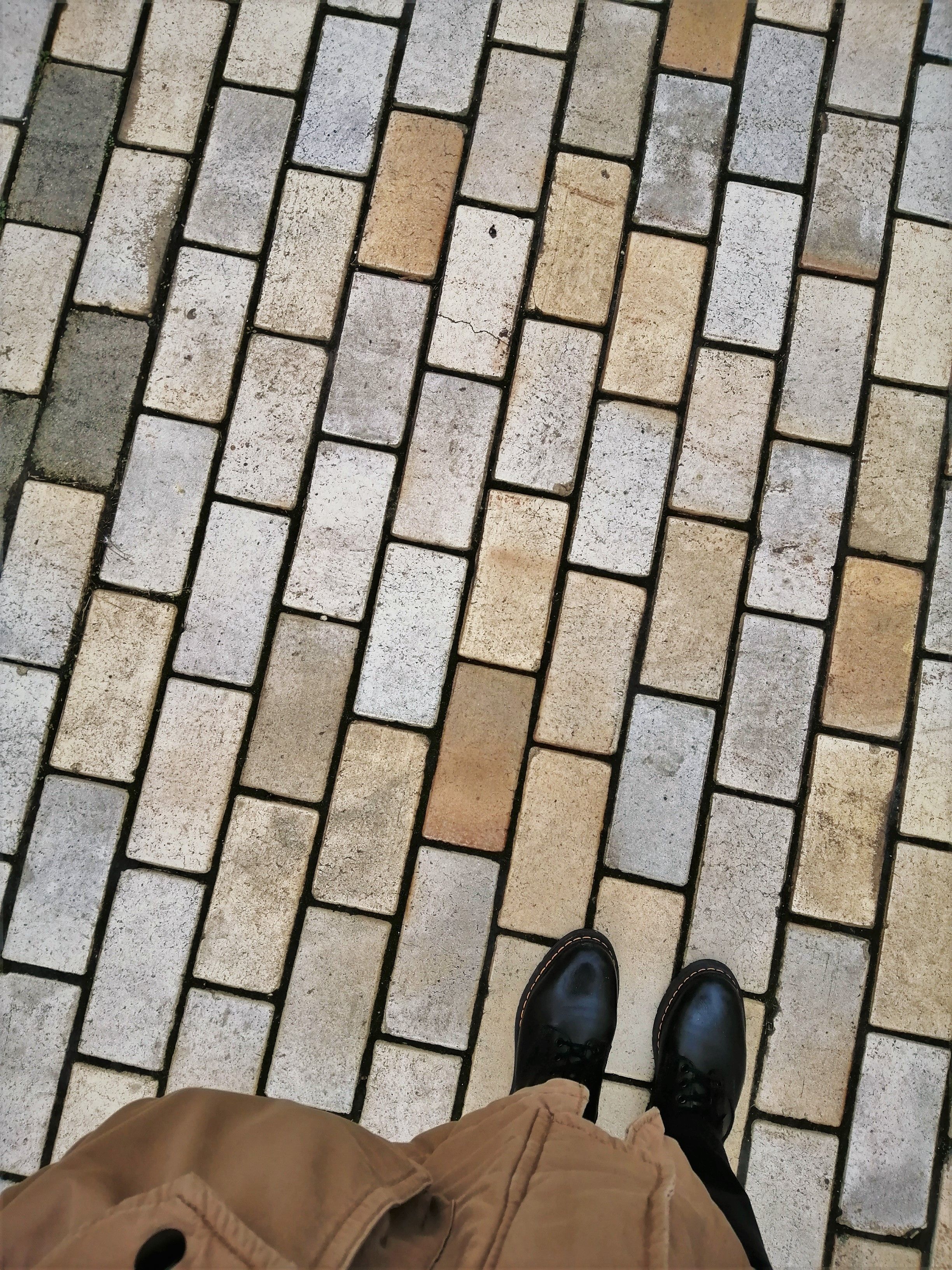 Stylish black leather shoes on a patterned pavement. High angle view in Kyiv city.