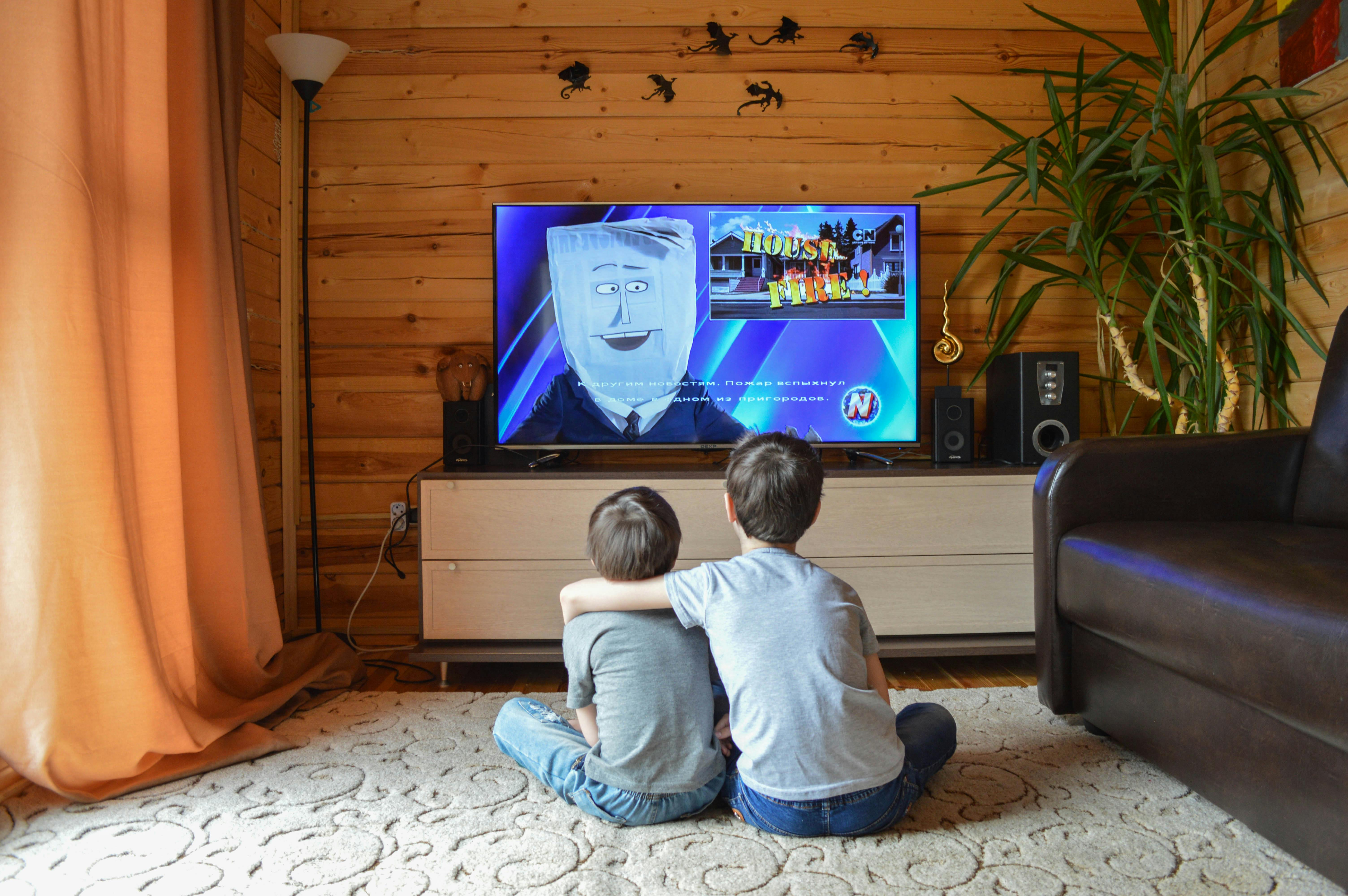 anonymous siblings cuddling and watching tv at home