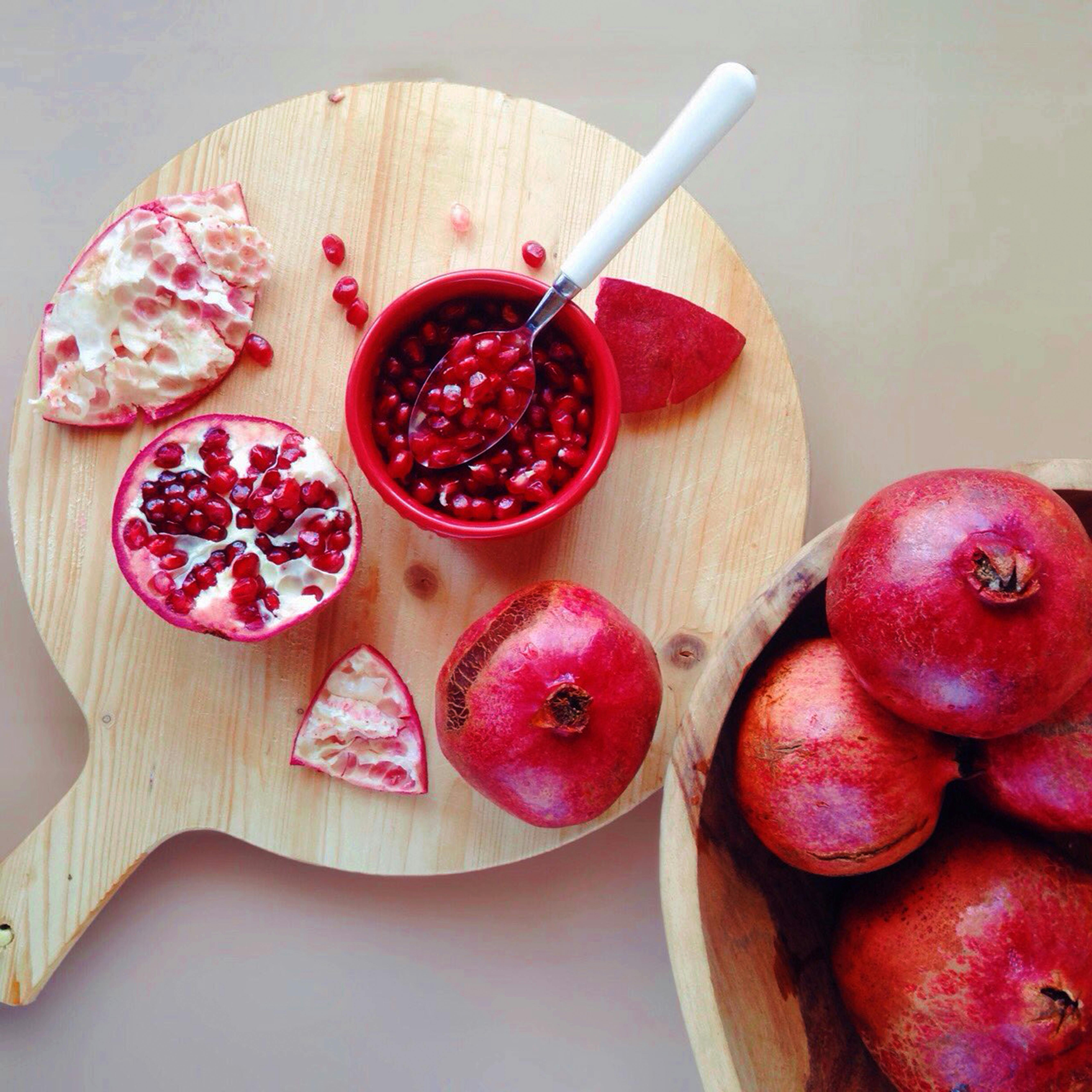 Fresh pomegranate seeds in a bowl on a wooden board, highlighting healthy eating.