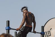 A Topless Man in Black Shorts Sitting on a Pull-Up Bar