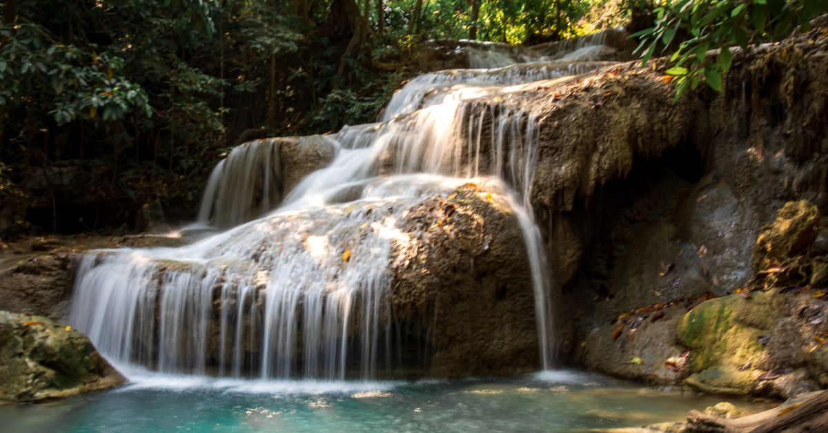 A waterfall cascading into a turquoise pool in a tropical forest