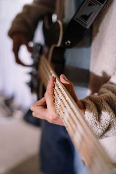 Close-up shot of a musician strumming a guitar indoors.