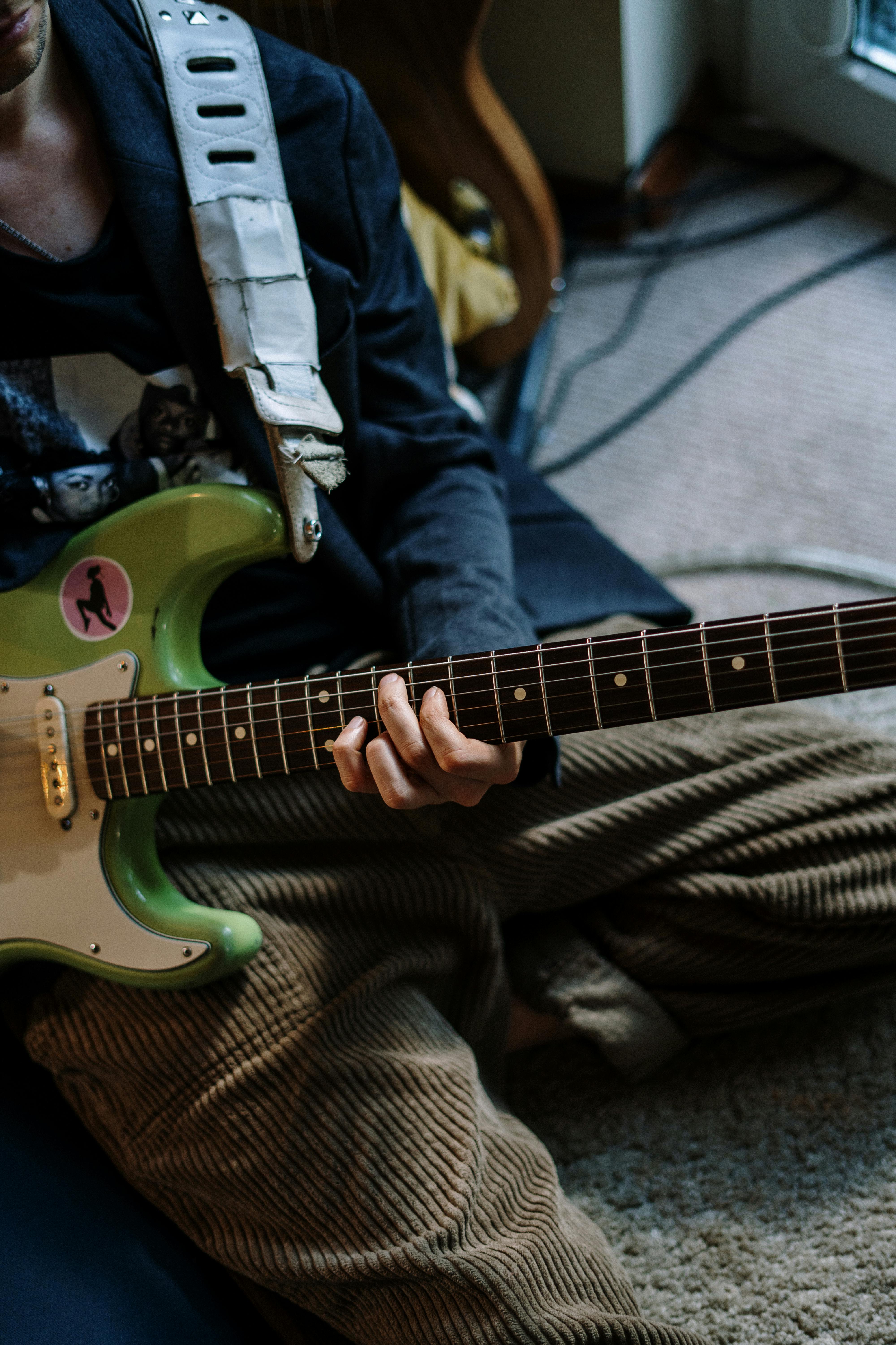 man in gray and white striped long sleeve shirt playing red electric guitar