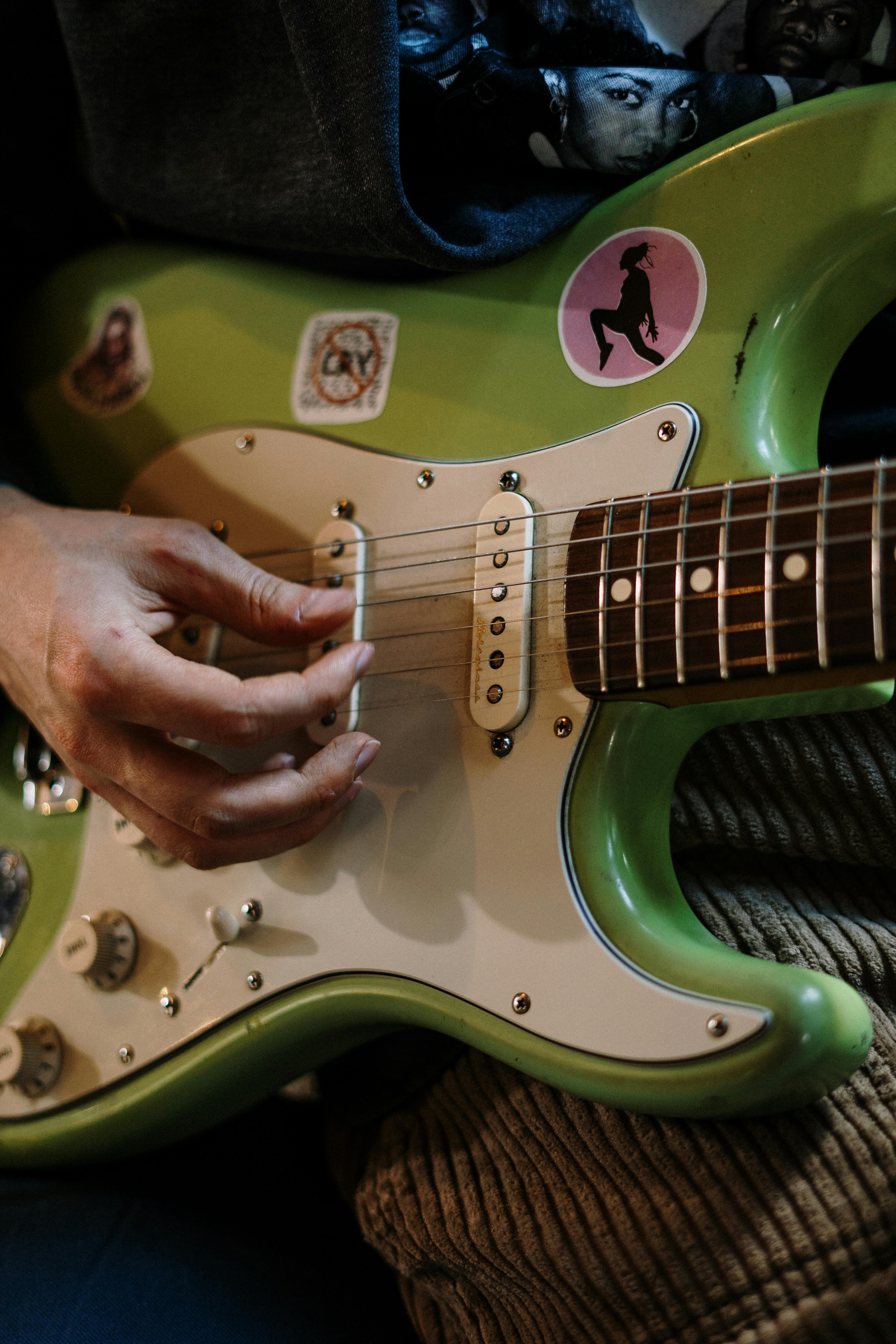 person playing green and white electric guitar