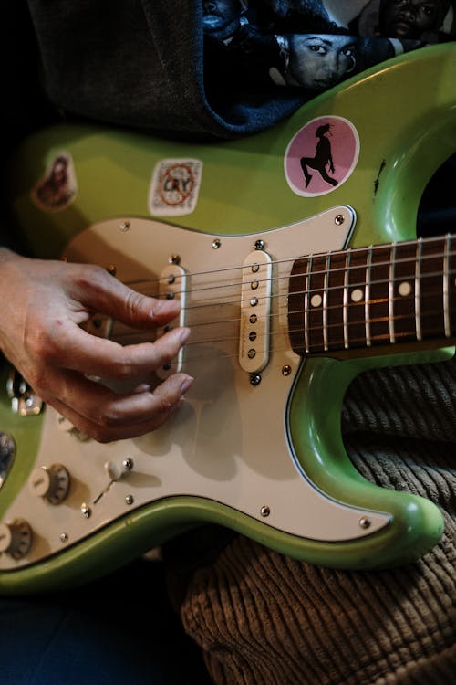 Person Playing Green and White Electric Guitar