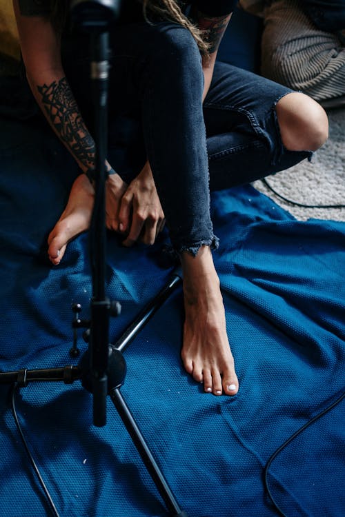 Person in Blue Denim Jeans Sitting on Blue Textile