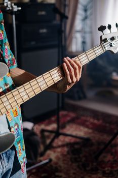 Close-up of a musician playing bass guitar in a cozy home studio.. close, musician, playing