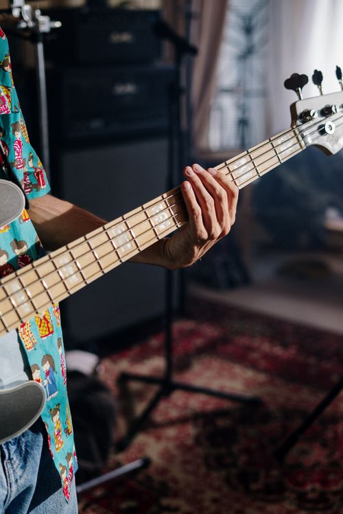 Free Close-up of a musician playing bass guitar in a cozy home studio. Stock Photo