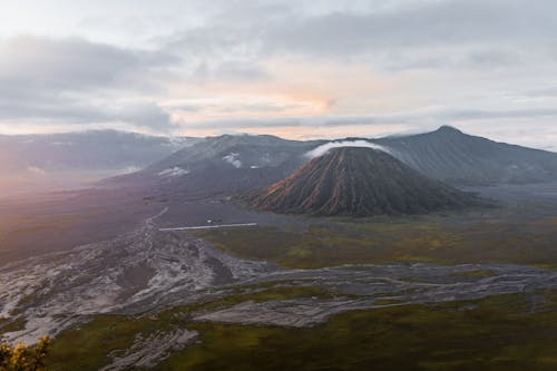 Majestic view of valley with mountains and volcano located in highland under cloudy sky