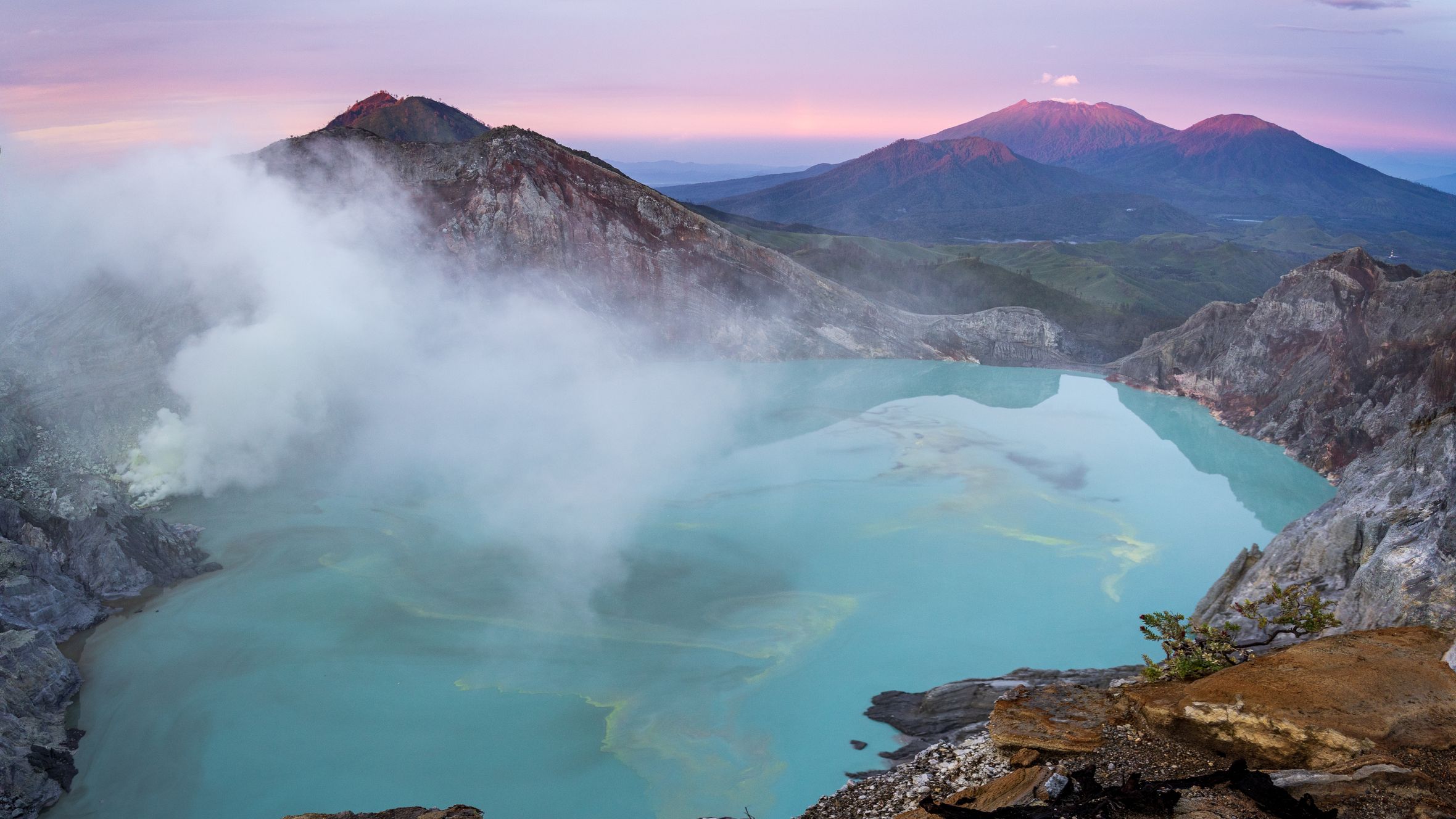 Amazing scenery of mountain ridge and hot spring with turquoise water under bright sunset sky