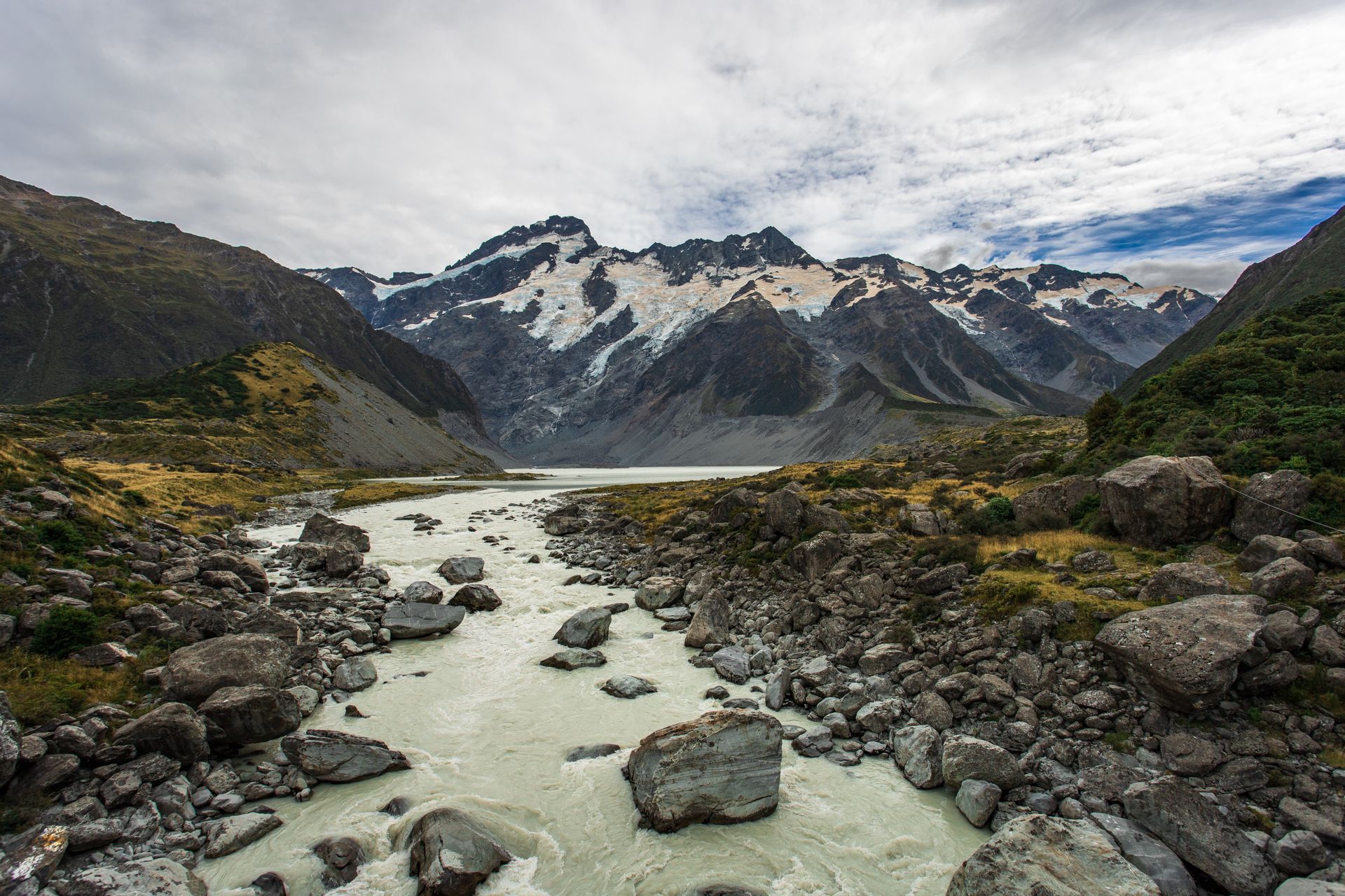 Spectacular landscape of mountains covered with green grass and mountain peaks under snow
