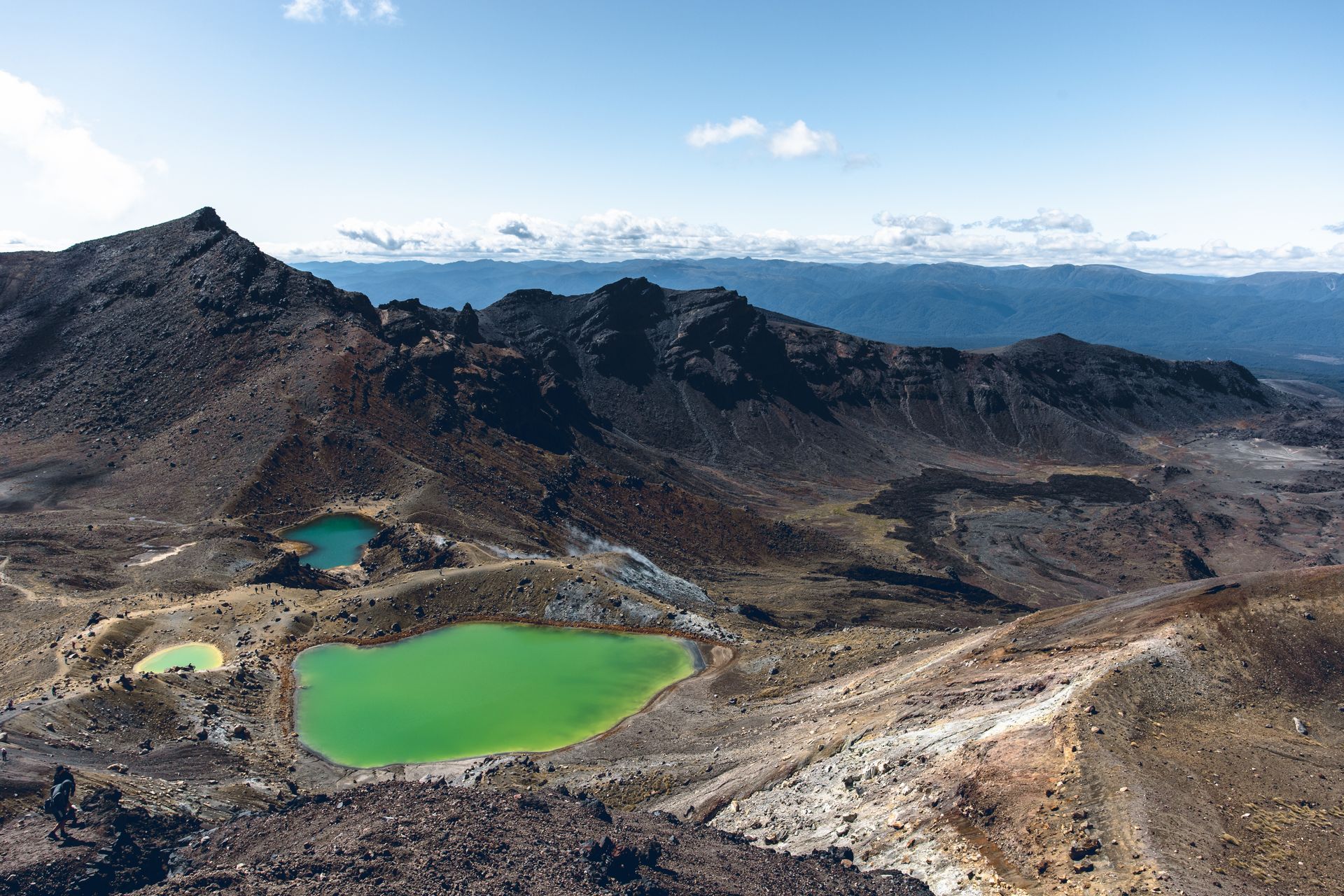 High angle of colorful lake located among desert highland with steep slopes in bright day