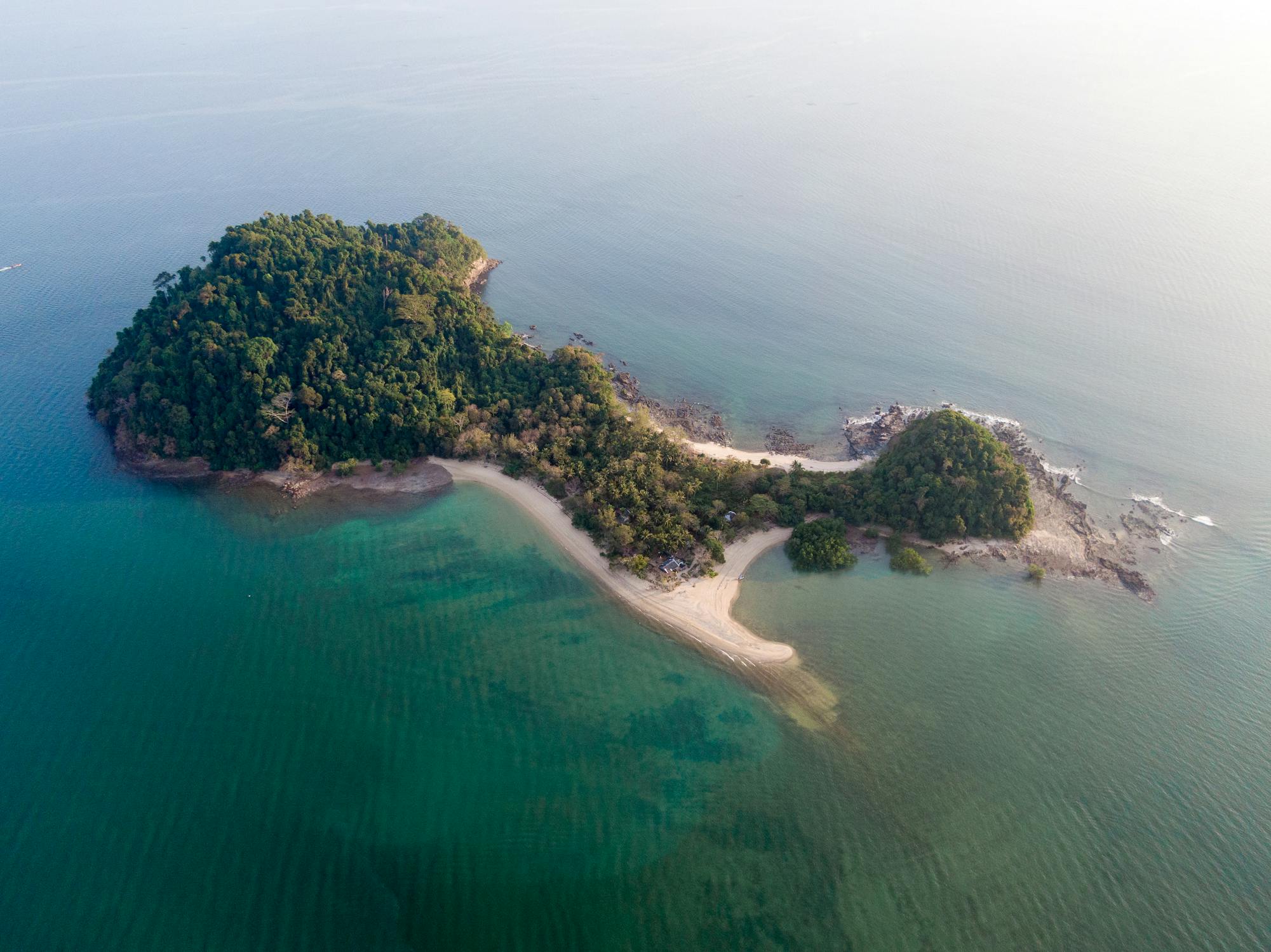 Green island with sandy shore in ocean